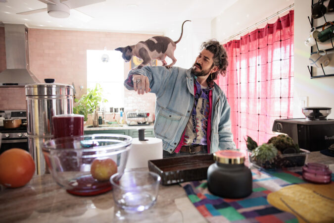 Franki Jupiter’s cat Nudo walks on his arm at home in Manayunk.
