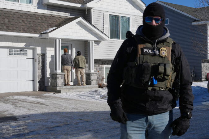 Federal agents knock on a door of a residence in Blaine, Minn.