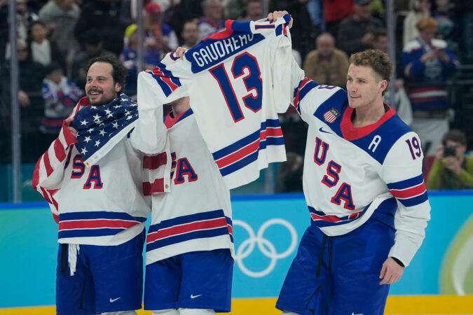 From left, Auston Matthews, Zach Werenski, and Matthew Tkachuk hold up Johnny Gaudreau's No. 13 jersey after Sunday's gold medal win at the Olympics.