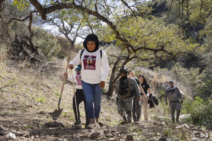 The Searching Mothers of Sonora, flanked by Mexico law enforcement, walk through a canyon during their search for Nancy Guthrie on Wednesday in Nogales, Mexico.