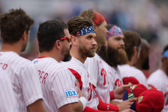 Phillies first baseman Bryce Harper (center) listens to the national anthem before the team's first spring training game Sunday against the Pittsburgh Pirates.