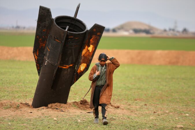 A shepherd boy walks away from an unexploded Iranian projectile that landed in an open field in the outskirts of Qamishli, eastern Syria, Wednesday.