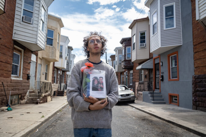Guillermo Santos Jr. holds the ashes of his father, Guillermo Santos Sr., who died of a fentanyl overdose in 2021, outside his childhood home near Kensington and Allegheny Avenues.