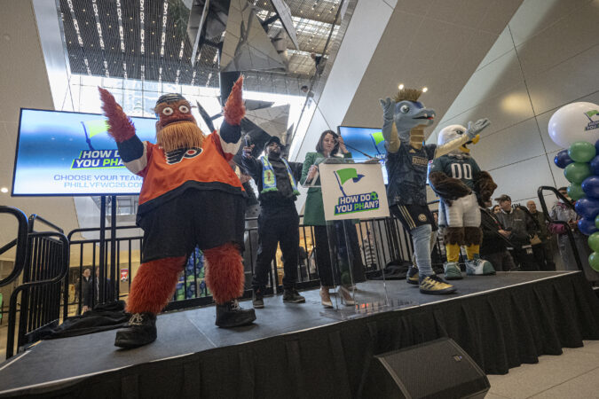 Eagles defensive end Brandon Graham alongside Meg Kane, host city executive and CEO of Philadelphia Soccer 2026, are surrounded by Philly sports mascots during Tuesday's event kicking off 100 days until the 2026 FIFA World Cup at the Comcast Center.
