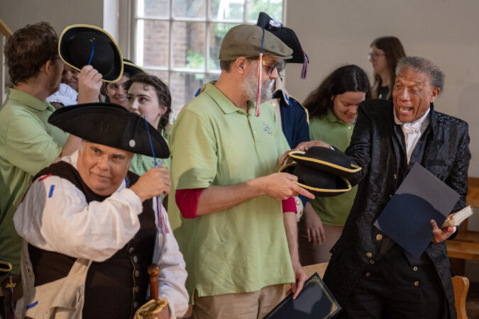 Coe Kummer (from left) as Jacob Hurltzhizer, a stable owner, storyteller Cubby Altobelli, and Robert Branch as the Rev. Richard Allen, join other historical reenactors at graduation on May 21, 2026, after weeks of intensive, immersive training at the Benstitute. The modern-dressed storytellers and period-costumed history makers with Once Upon a Nation received their diplomas at the Free Quaker Meeting House near Independence Hall and will take to the streets to immerse visitors and residents in 18th-century Philadelphia.