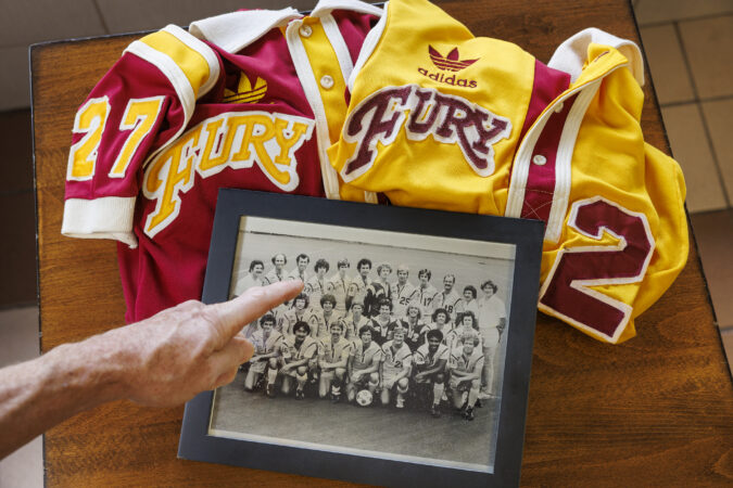 Kevin Murphy, who played for the Philadelphia Fury in the 1970s, points out a team photo along with a pair of old uniforms.