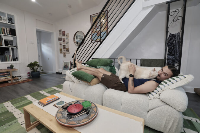 Dylan Foglesong and his Siamese cat, Jatto, in the living room of his home in Southwest Philly.