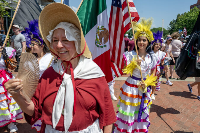 Historical interpreter for the American Revolution Diane Jost with the Sudbury (Mass.) Companies of Militia & Minute, walks with members of the Ballet Folklorico Mosaicos, dancers fro a Mexican cultural organization in Indianapolis, Ind. as groups not marching mingle on Independence Mall as Philadelphia celebrates America’s 250th birthday Friday, July 3, 2026 even after the Wawa Salute to Independence Semiquincentennial Parade was canceled amid a declared heat emergency with 100-degree temperatures.