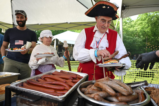 The Town Crier of Hopewell, N.J., and his wife, Stanley and Cindy Saperstein, attend Hopewell's USA 250th Town-Wide Block Party on June 6, 2026. John Hart, a signer of the Declaration of Independence, is buried at the Old School Baptist Church there.
